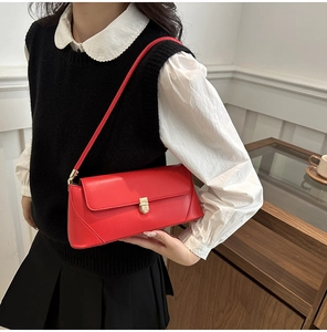 Close-up of bright red shoulder bag featuring elegant gold metal lock and smooth PU leather