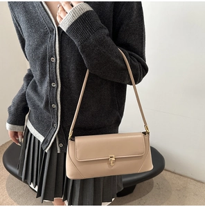 Detailed close-up of a beige leather baguette bag with a premium golden metallic clasp