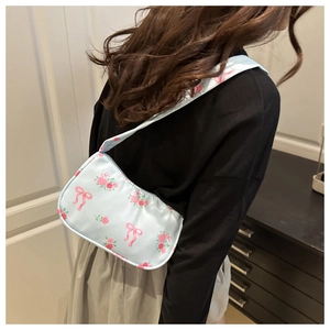 Close-up of light blue floral bag with pink rose patterns and bow details on satin