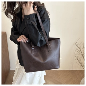 Dettaglio di una grande borsa tote marrone scuro in ecopelle portata a spalla da una modella