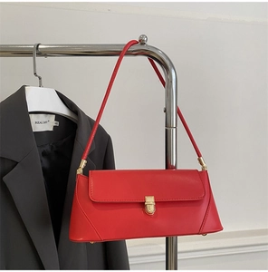 Detail of red leather baguette bag with golden metal buckle and sleek shoulder strap