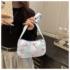 Detail of light blue floral underarm bag with pink roses and bow prints held by a model