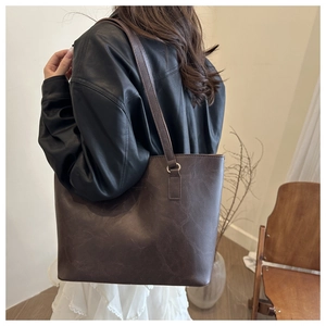 Detailed side view of a large vintage brown leather tote bag worn by a model