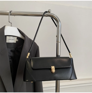 Detail view of a black leather underarm bag featuring a golden buckle and metal accents