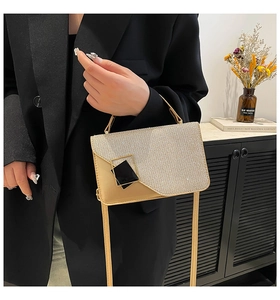 Detail of champagne gold glitter handbag with black and gold square buckle accessory