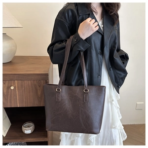 Detailed view of large dark brown retro tote bag with pleated texture and gold hardware