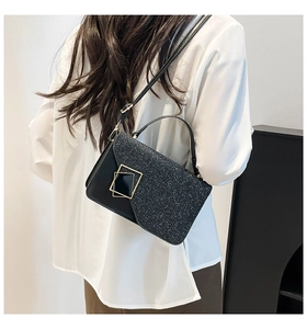 Detail shot of the black glitter flap and golden geometric buckle on the crossbody bag