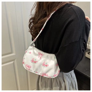 Detail of white underarm bag featuring pink rose clusters and ribbon bow prints