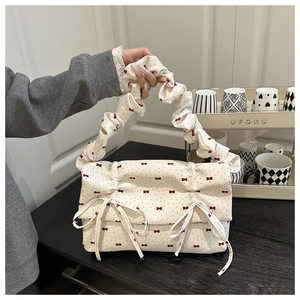 Detail of cream pleated handbag featuring red bows and black polka dot pattern