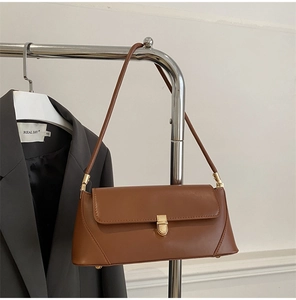 Detail of dark brown leather baguette bag with golden metal buckle and sleek rectangle shape