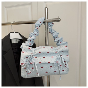 Detail view of light blue ruched handbag with red bow print and drawstring design