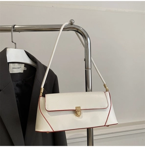 White baguette bag with red edges and golden buckle hanging next to a blazer