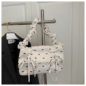 Detail of white pleated handbag with red bow print and soft ruched top handle