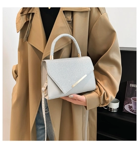 Detail of silver glitter flap and light grey leather handbag with golden hardware