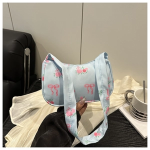 Close-up of light blue satin handbag with pink floral prints and ribbon patterns