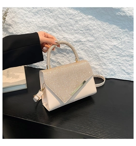 Detail of cream envelope handbag featuring sparkling rhinestone flap and round handle
