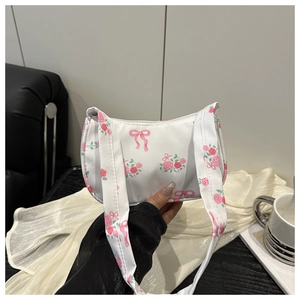 Detailed close-up of a white shoulder bag with pink rose patterns and bow prints