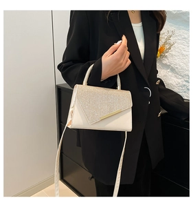 Close-up of cream shoulder bag with sparkling sequins and gold metal trim handle