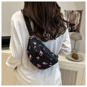 Détail d'un sac selle en nylon noir avec imprimé roses roses porté sur le dos du mannequin