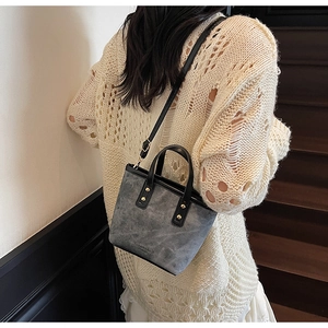 Detailed view of grey distressed leather bucket bag worn by model in retro style