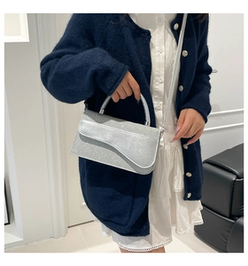 Silver glitter square bag featuring a curved flap design and metallic top handle