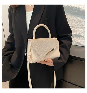 Detailed view of the rhinestone-embellished handle and metallic trim on the white bag