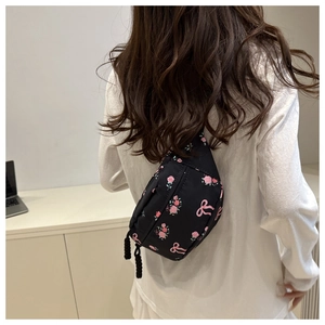 Détail d'un sac en nylon noir avec imprimé de roses roses et de nœuds rubans