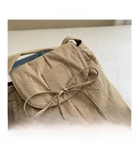 Detail shot of the crinkled nylon fabric and decorative bow tie on this beige tote bag
