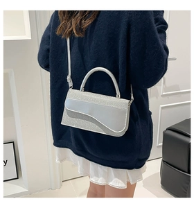 Silver sequin crossbody bag styled on shoulder with metallic curved flap detail