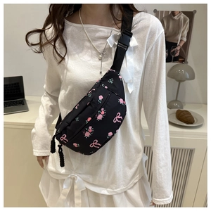 Detail of black crossbody bag featuring pink floral print and adjustable buckle strap