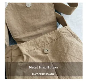 Detail of the high-quality metal magnetic closure and textured fabric on the khaki bag