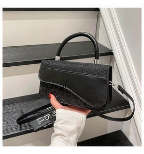Detail of black glitter crossbody bag with metallic sheen and saddle-shaped flap design