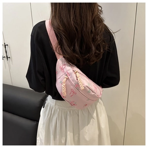 Gros plan d'un sac bandoulière en nylon rose à fleurs porté par un mannequin en intérieur