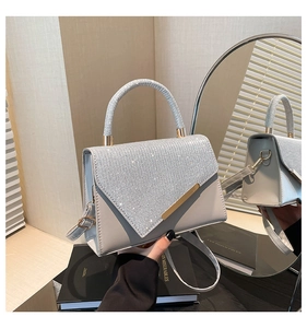 Close-up of shimmering silver crossbody bag with diamond-studded flap and gold trim details