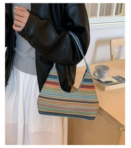 Detail of multi-color woven shoulder bag showing vibrant striped texture and crescent shape