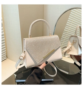 Detailed view of the rhinestone embellished flap and golden trim on a cream mini square bag