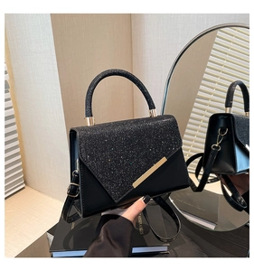 Detail of black glitter handbag with V-shaped flap and elegant gold metallic trim