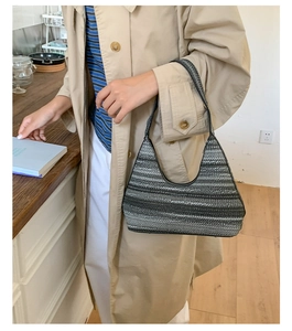 Detail of striped hobo shoulder bag paired with a classic khaki trench coat for daily commute