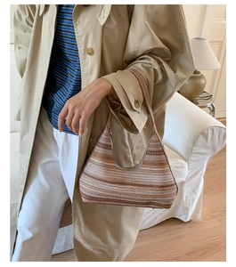 Close-up of woven straw shoulder bag featuring tan and cream striped texture on a hobo shape