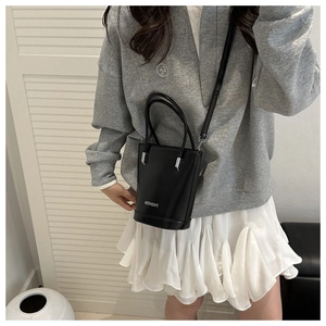 Detail of black matte bucket bag with white fashion text and silver hardware accents