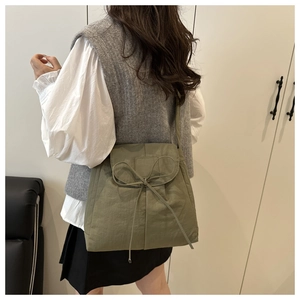 Detail view of olive green nylon crossbody bag featuring a decorative drawstring bow knot