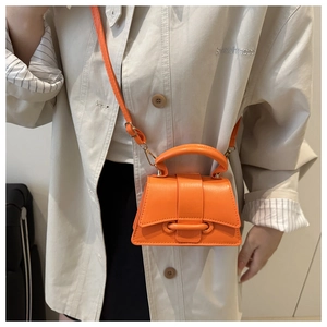 Close-up of vibrant orange mini handbag with curved bottom and ring buckle detail