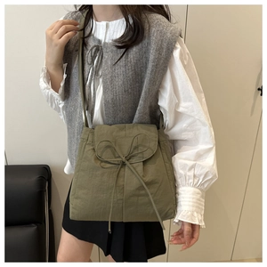 Close-up of olive green ballet-style shoulder bag with decorative bow and canvas texture