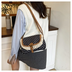 Close-up of retro polka dot crossbody bag with lace trim and brown leather strap details