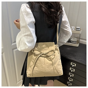 Detail shot of khaki nylon tote bag featuring a large bow drawstring on the back of model