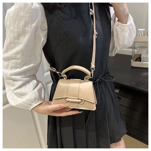Detail of a beige hourglass-shaped crossbody bag with fixed handle and shoulder strap