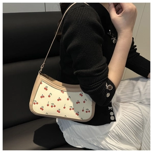 Chic beige underarm bag with red cherry print styled with white pleated skirt