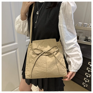Detail of khaki nylon crossbody bag with adjustable strap and decorative bow knot