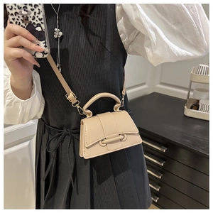 Detail of beige PU leather mini crossbody bag featuring a unique tonal buckle and gold hardware