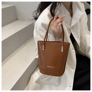 Close-up of caramel brown leather bucket bag with silver metal FASHION logo and handle